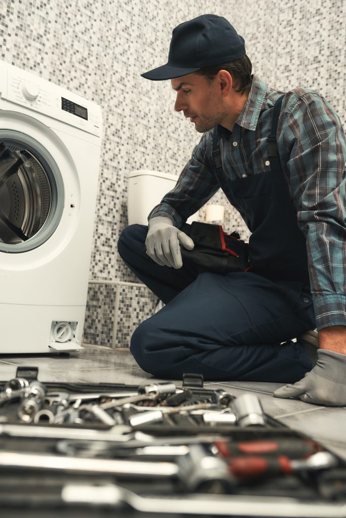 Finding a solution. Plumber repairing washing machine